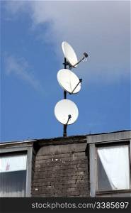 Three satellite dishes on a roof, pointing in different directions