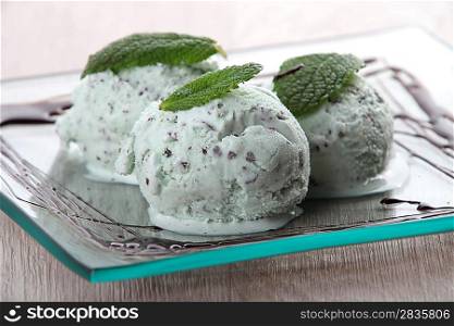 Three scoops of mint choc chip ice cream on a square plate
