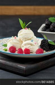 Three scoops of white ice cream in a round plate with mint leaves on a black table