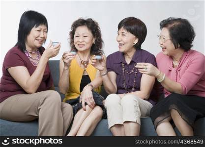Three senior women and a mature woman holding tea cups and smiling