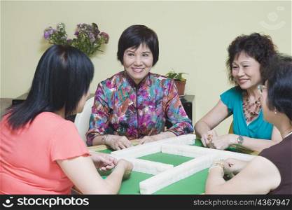 Three senior women and a mature woman playing mahjong