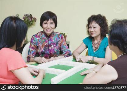 Three senior women and a mature woman playing mahjong
