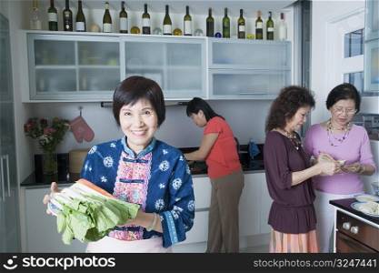 Three senior women and a mature woman preparing food in a domestic kitchen