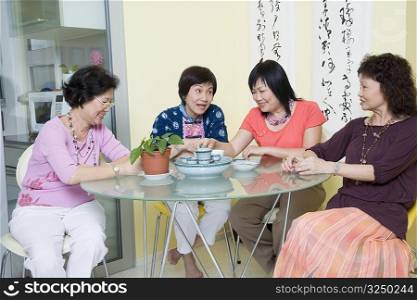 Three senior women and a mature woman sitting at a table