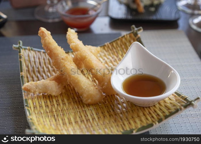 Three Shrimps tempura with soy sauce on yellow bamboo plate. Seafood tempura dish of traditional asian cuisine