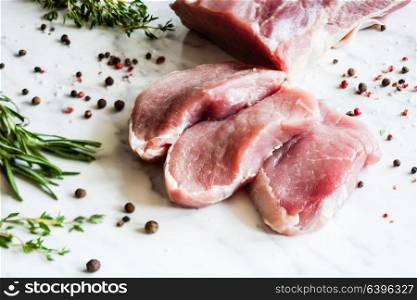 Three slices of raw pork tenderloin with spices. Fresh pork meat