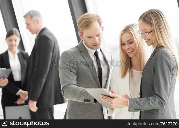 Three smart employees discussing documents using tablet pc at meeting. Employees at meeting