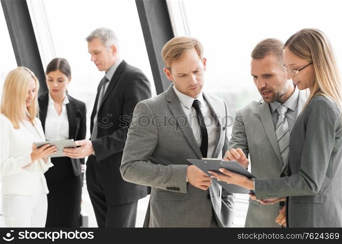 Three smart employees discussing documents using tablet pc at meeting. Employees at meeting