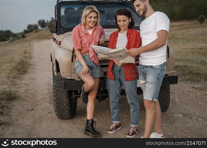 three smiley friends checking map while traveling by car