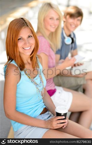 Three smiling college student friends sitting summer time relax break
