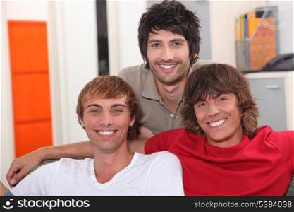 Three smiling lads sitting on a sofa