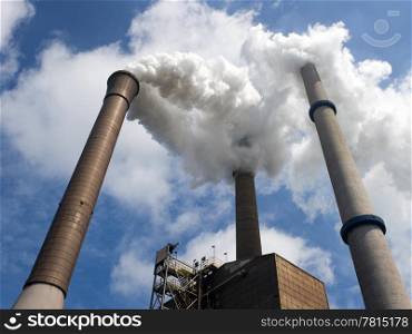 Three smoke stacks, emitting steam, with a centered and vertical vanishing point