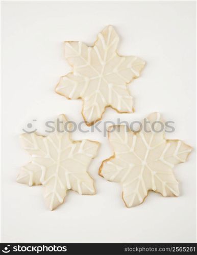 Three snowflake sugar cookies with decorative icing.