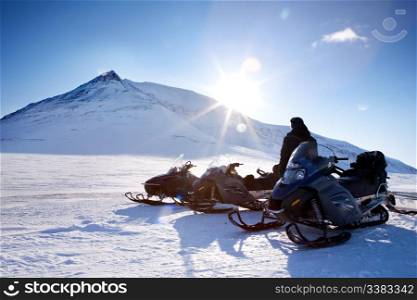 Three snowmobiles and a winter landscape with mountain
