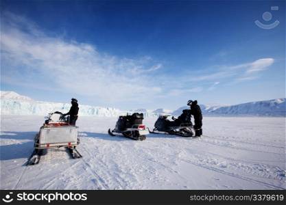 Three snowmobiles in front of a glacier, Svalbard, Norway