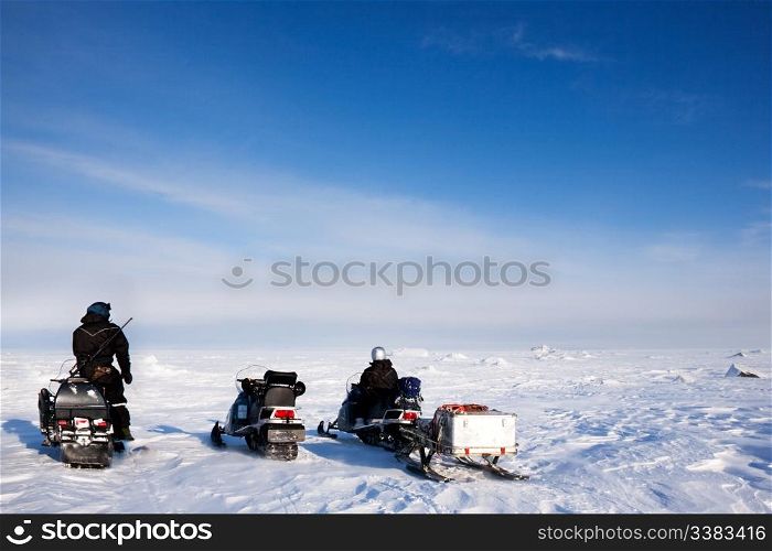 Three snowmobiles on a svalbard landscape of barren snow