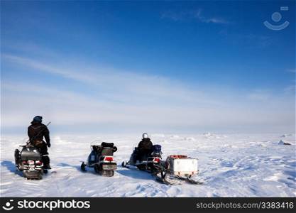 Three snowmobiles on a svalbard landscape of barren snow
