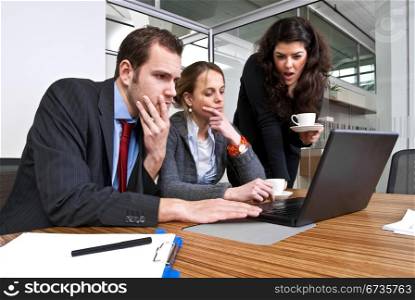 Three staff members discussing financial matters whilst browsing a laptop