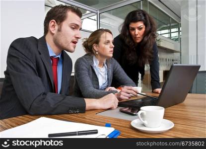 Three staff members discussing financial matters whilst browsing a laptop