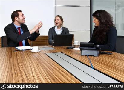 Three staff members enjoying a joke, during an office meeting