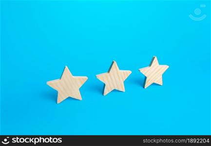 Three stars on a blue background. Rating evaluation concept. Service quality. Buyer feedback. High satisfaction. Popularity rating of a restaurant, hotel or mobile applications. Good reputation status
