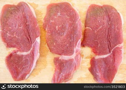 Three steaks raw salted pork on cutting board