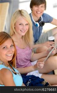Three student friends sitting with tablet smiling at camera