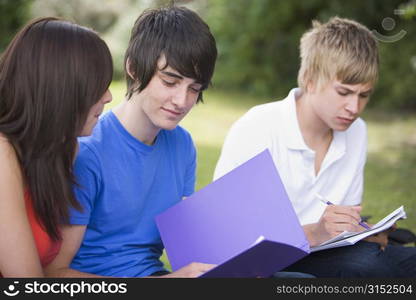 Three students outdoors studying (selective focus)