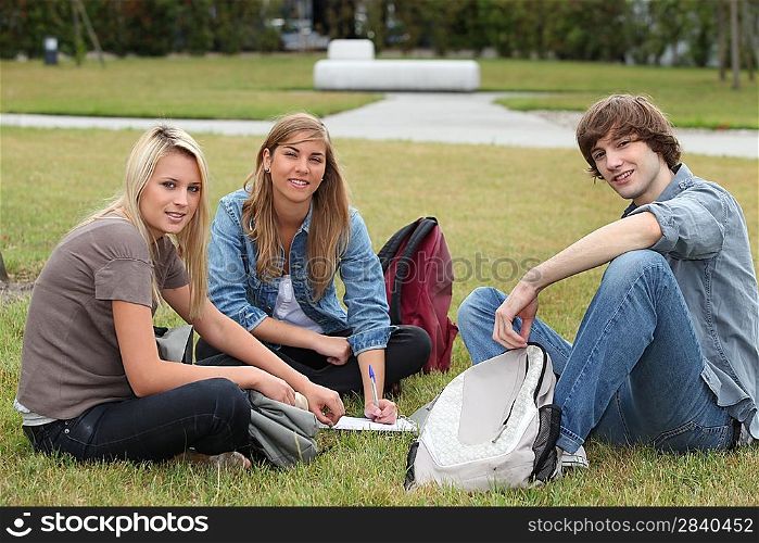 Three students sat in the park working