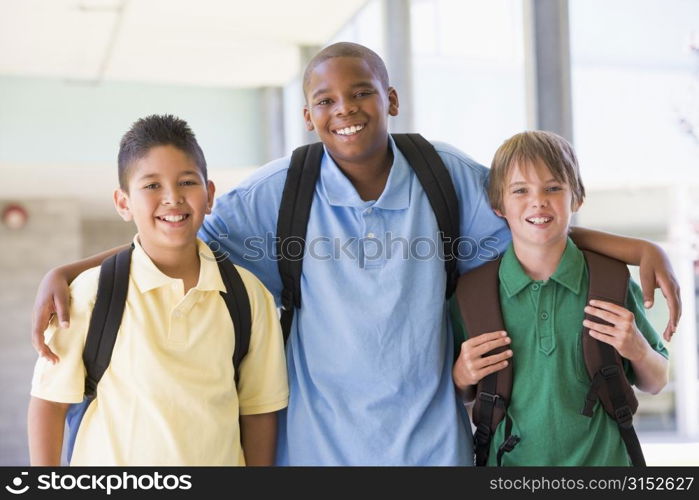 Three students standing outside school together smiling (high key)