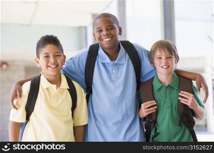 Three students standing outside school together smiling (high key)