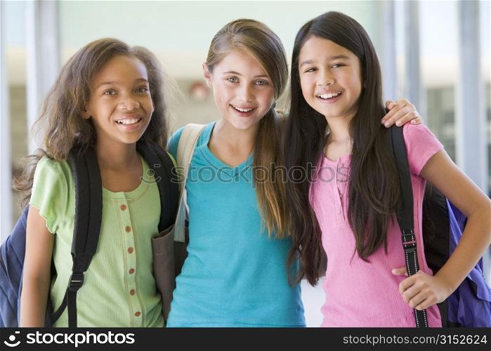 Three students standing outside school together smiling (selective focus)