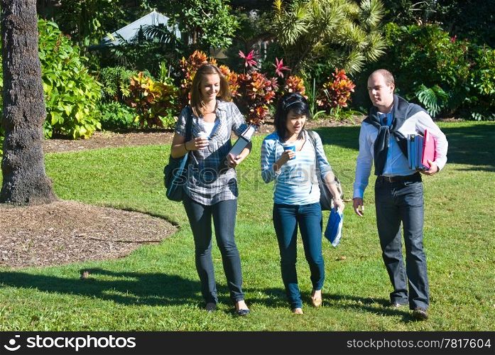 Three students walking through the botanical gardens, on their way to class