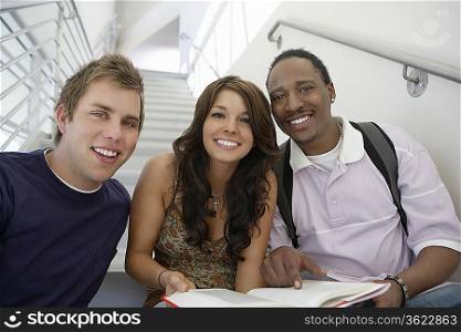Three students working on stairs in school, portrait