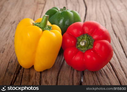 three sweet peppers, wooden table background