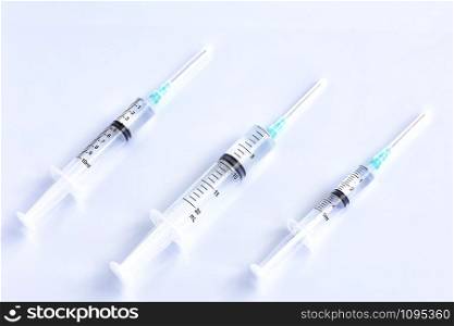 Three syringes of different capacity on a white table, prepared for injection in the hospital with copyspace for text... Several different syringes on a light smooth table, ready to use.