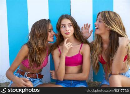 Three teen best friends girls funny whispering gesture in a beach stripes background
