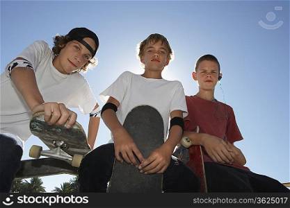 Three teenage boys (16-17) with skateboards, outdoors, portrait