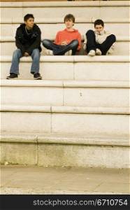 Three teenage boys sitting on steps