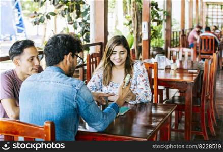 Three teenage friends on their cell phones in a coffee shop. Young friends in a coffee shop with their cell phones having a good time. Three people in a coffee shop with phones having a good time