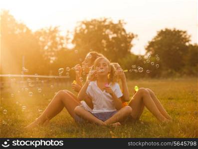 Three teenage girls have fun in the park. Two friends outdoor. Summer people doing bubbles