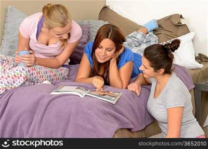 Three teenage girls reading at slumber party in pajamas
