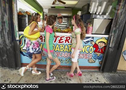 Three teenage girls talking with a bartender in a juice bar