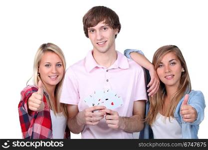 Three teenagers displaying a deck of cards and giving the thumbs up