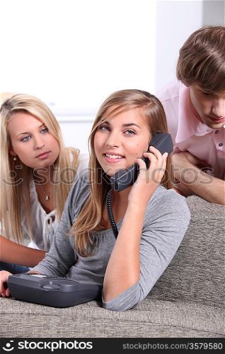 Three teenagers making a telephone call
