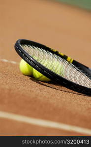 Three tennis balls under a tennis racket