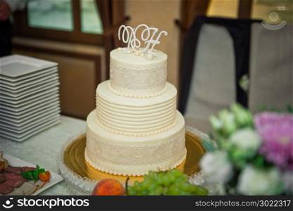 Three-tiered white-and-beige cake for the wedding.. Beautiful simple wedding cake 515.