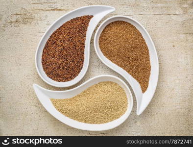 three tiny gluten free grains - kaniwa, amaranth and teff on teardrop shaped bowls against white painted rustic wood