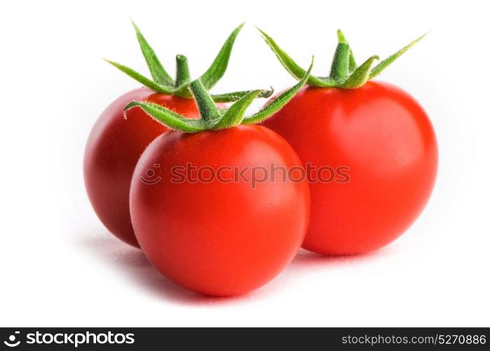 Three tomatoes on white. Three small fresh tomatoes with green leaves isolated on white background