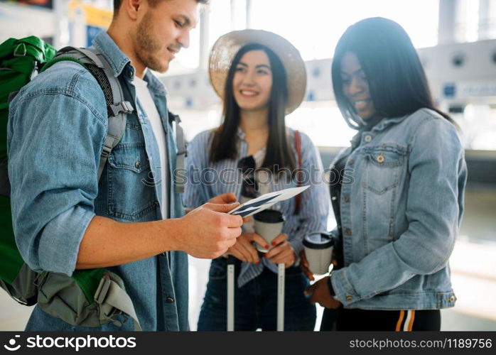 Three tourists with luggage waiting for departure in airport. Passengers with baggage in air terminal, happy journey. Three tourists with luggage waiting in airport